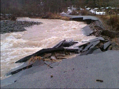 flooded river washing out roadway